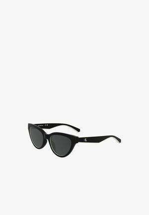 Lunettes de soleil noires en forme d'œil de chat, avec des verres gris. La monture inclut des accents blancs sur les bords et un logo sur la branche.