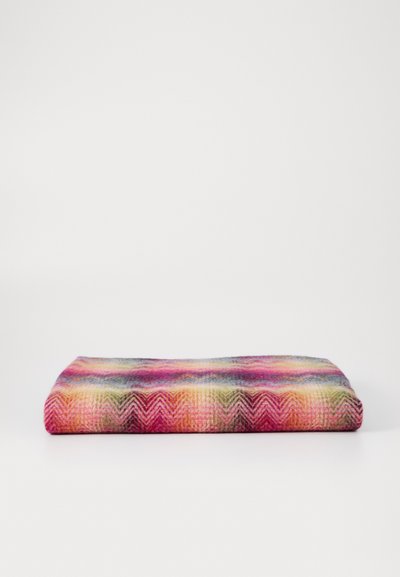 Vævet tæppe med et chevron-mønster i levende farver, herunder pink, lilla og grøn, med en blød tekstur og foldet design.