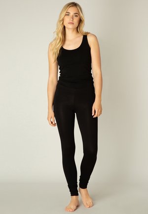 Zwarte tanktop en legging gemaakt van een zachte, rekbare stof. De tanktop heeft brede schouderbanden, terwijl de leggings taps toelopen bij de enkels.