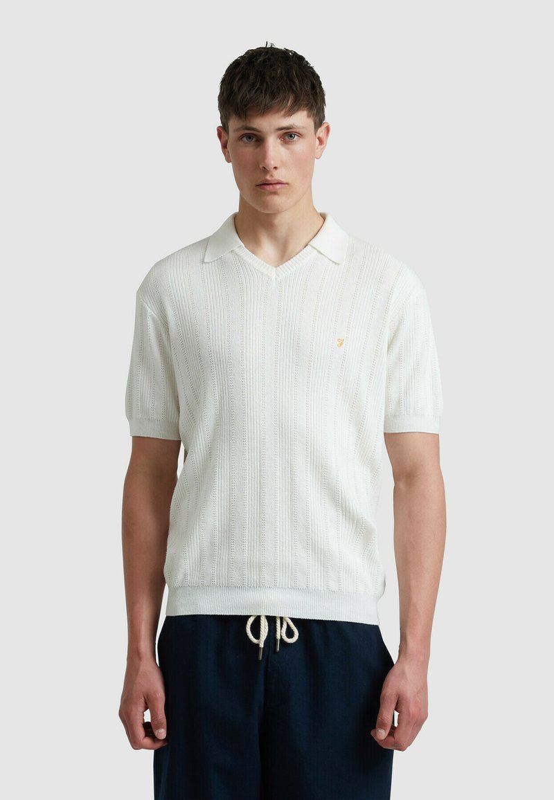 Weißes kurzärmeliges Strickpolo mit strukturiertem Muster und V-Ausschnitt. Mit kleinem goldenen Logo auf der Brust und gerippten Bündchen.