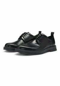 Black lace-up shoes featuring a shiny leather upper, rounded toe, padded collar, and a contrasting red accent on the sole.