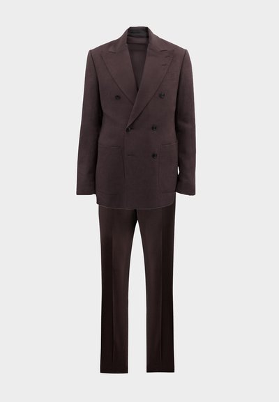 Completo doppiopetto marrone scuro con ampi revers, bottoni neri, tasche a toppa e pantaloni dritti coordinati su uno sfondo chiaro.