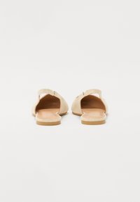 Sandales slip-on beiges à dos ouvert, en tissu doux, avec un design arrondi et une semelle légère pour le confort.