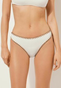 Weißer gerippter Bikiniunterteil mit brauner gewellter Kante. Verf�ügt über eine mittlere Bundhöhe und ein strukturiertes Material. Glatte Innenauskleidung.