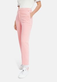 Pink corduroy pants with a straight cut, featuring side pockets and a drawstring waist. Paired with white sneakers and socks.