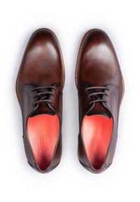 Scarpe stringate in pelle marrone con finitura testurizzata, caratterizzate da una tomaia liscia e solette rosse vivaci. Design classico con punta appuntita.