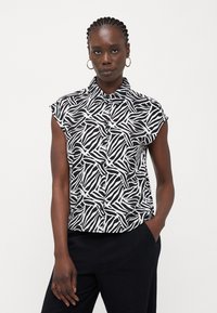 Μπλούζα κοντό μανίκι με μαύρο και άσπρο αφηρημένο σχέδιο, κουμπιά μπροστά και χαλαρή εφαρμογή. Φτιαγμένη από ελαφρύ ύφασμα.