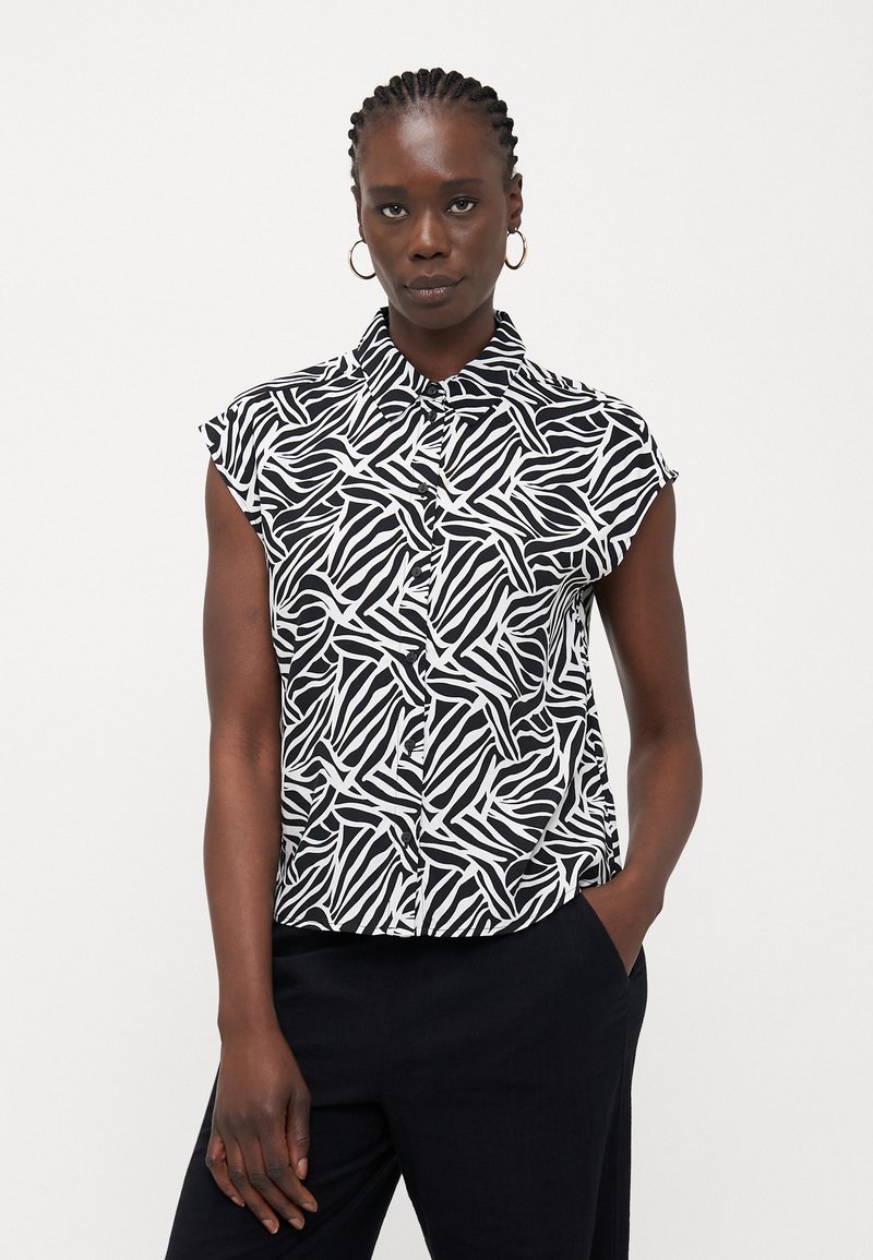Blusa de manga curta com um padrão abstrato em preto e branco, frente abotoada e um ajuste descontraído. Feita de tecido leve.