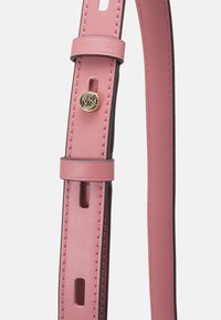 Bandoulière en cuir rose avec des bords noirs, comportant un logo circulaire doré et des trous réglables pour une personnalisation. Fini texturé.