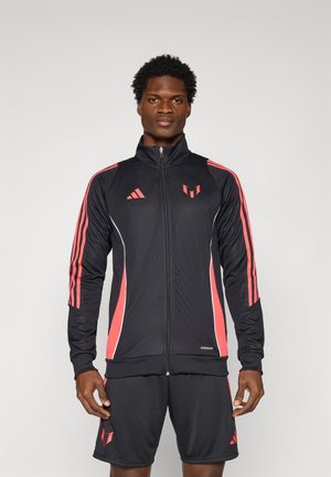 Sort atletisk jakke med røde striber og accenter, med fuld lynl�ås, høj krave og logo. Kombineret med sorte shorts.