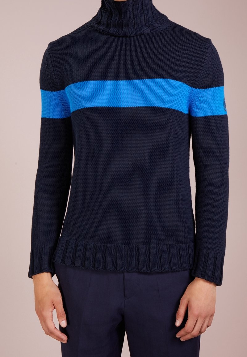 Pullover a maglia di colore blu navy con colletto alto e una striscia orizzontale di un blu brillante. Orlo e polsini a costine, tessuto testurizzato, design aderente.