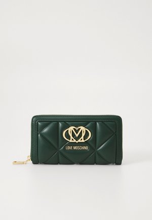 Green leather wallet featuring a quilted design, gold logo accent, and zip closure. Measures approximately 20 cm in width.