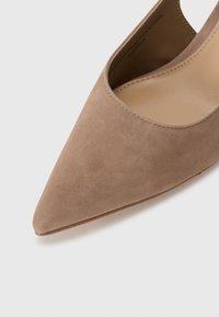 Scarpa beige in suede con punta a punta, scollatura bassa, texture liscia e design minimalista, che presenta linee pulite e una silhouette classica.