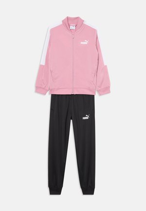 Giacca sportiva rosa con dettagli bianchi e zip frontale, abbinata a pantaloni neri con vita elasticizzata e logo. Materiale: tessuto sintetico.