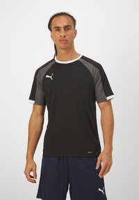 Sort atletisk t-shirt med grå paneldetaljer og hvid trim. Logo vist på venstre bryst. Korte ærmer, glat tekstur.