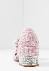 Rosa tweed-högklackad sko med en texturerad yta, med en kristalldekorerad silverbas och en dekorativ rosett på sidan.