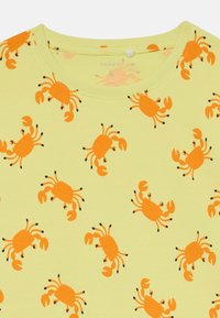Gelbes kurzärmeliges Hemd mit einem wiederholten Muster von orangefarbenen Krabben mit schwarzen Akzenten. Der Stoff ist weich und hat einen runden Halsausschnitt.