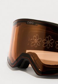 Primer plano de gafas de esquí CHPO de tono naranja con acolchado de espuma negra y reflejos de flores en la lente frente a un fondo blanco.