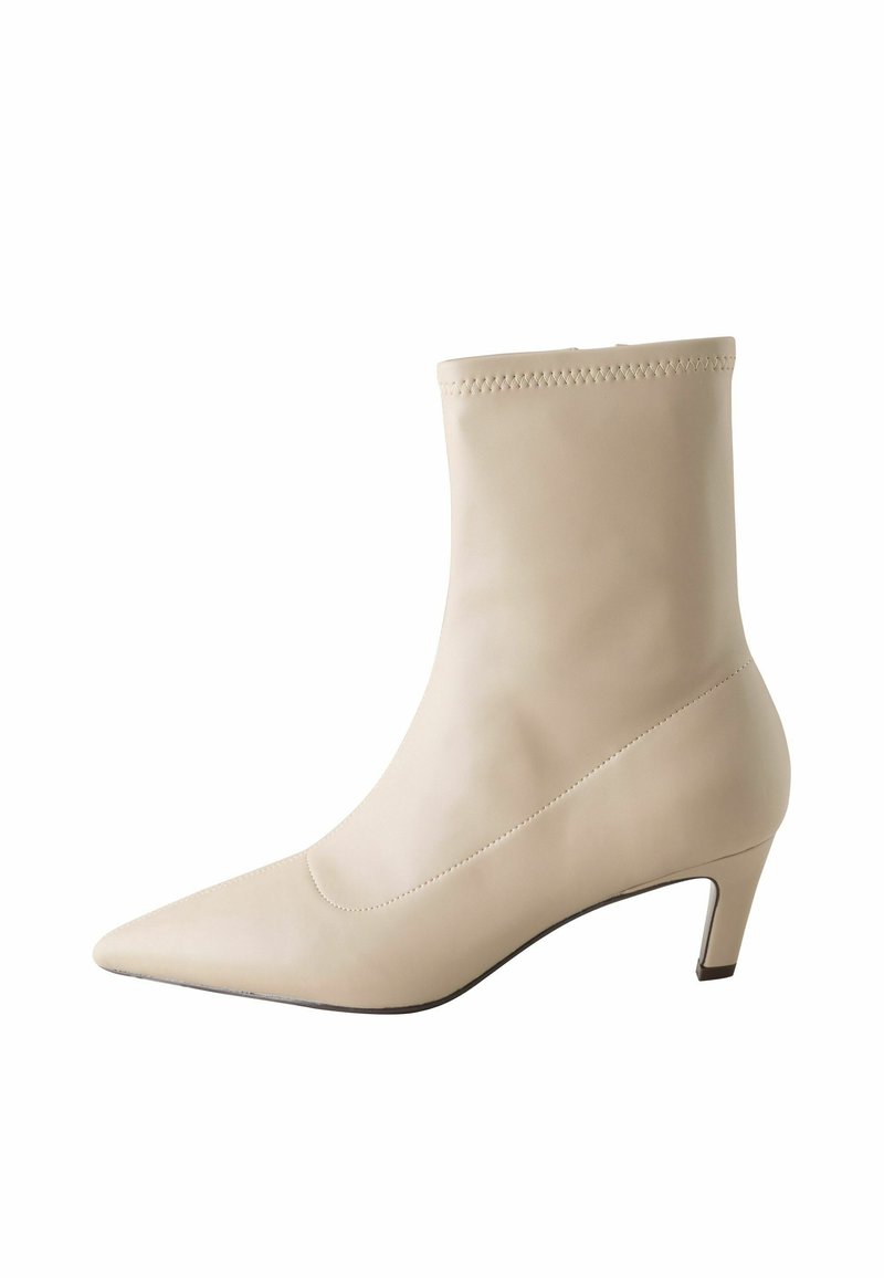 Beige læder ankelstøvle med spids tå og lav blokhæl. Glat tekstur, minimalistisk design med diskrete syningsdetaljer øverst.