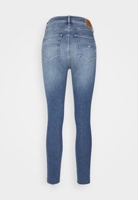 Jeans ajustados de denim azul desvanecido. Presentan una cintura alta, dos bolsillos traseros con solapas en ángulo y un parche de cuero con la marca en la parte trasera.