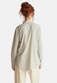 Camicia a righe in tessuto leggero, con maniche lunghe, colletto e una vestibilità morbida con orlo curvo. Colore: crema con righe più scure.