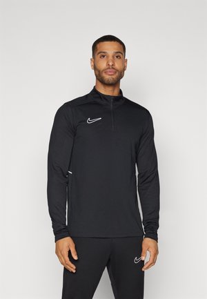 Svart långärmad sporttopp med dragkedja vid kragen, med vit Nike-logga och detaljer, tillverkad av ett slätt, lätt tyg.
