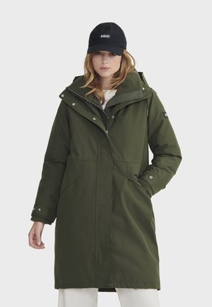 Groene parka met een ritssluiting aan de voorkant, drukknopen en een oversized capuchon. Bevat twee grote zijzakken en een zachte, wollen kraag.