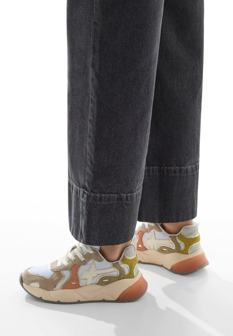 Sneakers con un design a materiali misti che presentano suede beige, mesh bianco e accenti verdi. Suola chunky con dettagli in gomma arancione.