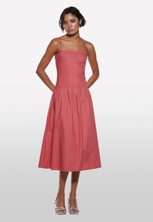 Robe midi de couleur rose poussiéreux, avec un corsage ajusté et une jupe plissée, dotée de fines bretelles et de poches latérales. Texture en coton lisse.