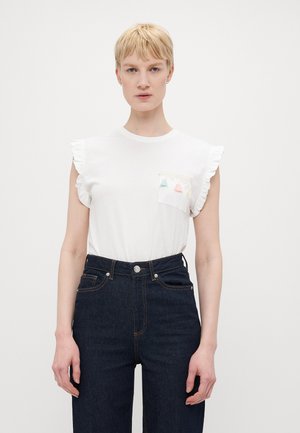 Witte t-shirt met korte mouwen en gerimpelde schouders, voorzien van een klein zakje met pastelkleurige driehoekige applicaties. Draagt met donkere high-waisted jeans.