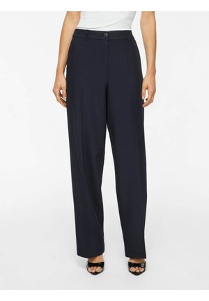 Pantalon noir coupe droite avec fermeture bouton et zip, porté avec des talons ouverts noirs et un haut blanc, montré de la taille aux pieds.