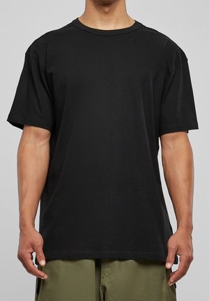 Czarny t-shirt z krótkim rękawem, wykonany z bawełny, z okrągłym dekoltem i luźnym krojem. Gładka struktura bez widocznych wzorów czy akcentów.