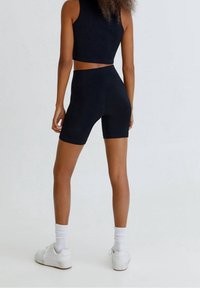 Top corto de canalé azul marino y pantalones cortos de ciclista a juego, diseño ajustado, textura suave, con zapatillas blancas y calcetines de caña baja.