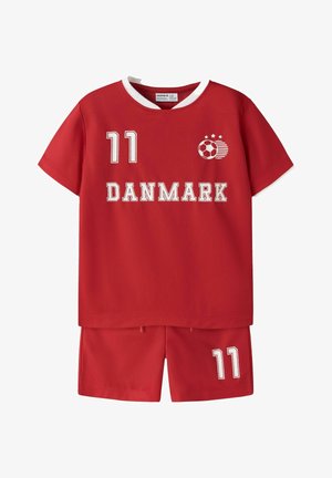 Rood sporttenue bestaande uit shirt en korte broek met witte kraag, nummer 11 op shirt en broekje, tekst "DANMARK" en voetballogo met drie sterren.