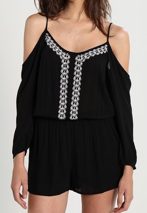 Czarny kombinezon z odsłoniętymi ramionami, długimi rękawami i białymi, pionowymi, haftowanymi wzorami na przedniej części gorsetu.