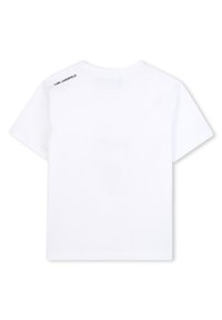 Bílé bavlněné tričko s krátkými rukávy. Má kulatý výstřih a černé logo vytisknuté na zádech v blízkosti ramene. Jednoduchý design.