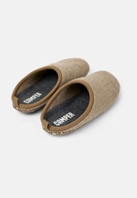 Pantofole in feltro marrone con forma arrotondata, tessuto testurizzato e una soletta grigio scuro. Presentano il logo "CAMPER" e un profilo tan a contrasto.