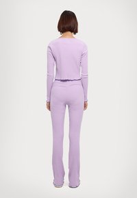 Purple ribbed crop top and flared pants set, featuring a scalloped trim. Smooth texture, fitted silhouette, and long sleeves.