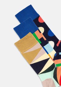 Mehrfarbige Socken mit einem blauen Rippenbund, geometrischen Mustern in Beige, Marineblau und Minzgrün sowie Punkten und Formen in verschiedenen Farben.