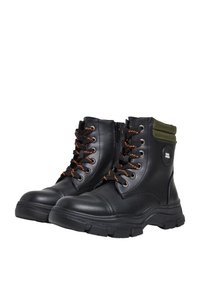 Botas de tobillo de cuero negro con cordones naranjas, suela duradera, acento de tela verde en el cuello y cremallera lateral para facilitar su puesta.