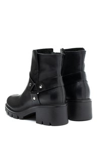 Mustat nahkaiset nilkko-bootsit, joissa on pyöreä kärki, paksu tukkikorko, koristeelliset hihnat metallidetalleilla ja sivuvetoketjukiinnitys.