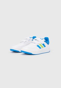 Balti sportiniai bateliai su mėlynomis detalėmis, žaliai mėlynomis juostelėmis, užsegimu su lipduku ir tekstūruotu padu sukibimui. Švarus dizainas.