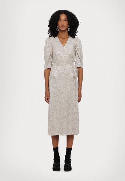 Silbernes Wickelkleid mit kurzen Puffärmeln, strukturierter Stoff, knielange Länge, gebundenem Gürtel in der Taille, kombiniert mit schwarzen Socken und Schuhen.