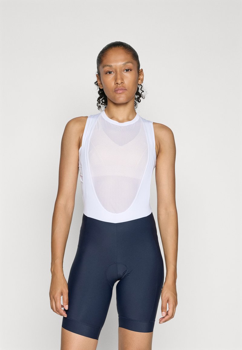 Hvid ærmeløs cykelbluse med mesh-detaljer og marineblå cykelshorts, der har en tætsiddende pasform og tekstureret stof.