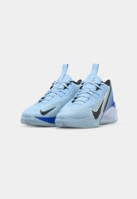 Light blue athletic shoes with textured upper, black accents, prominent Nike swoosh, and a molded, supportive sole. Adjustable lace design.