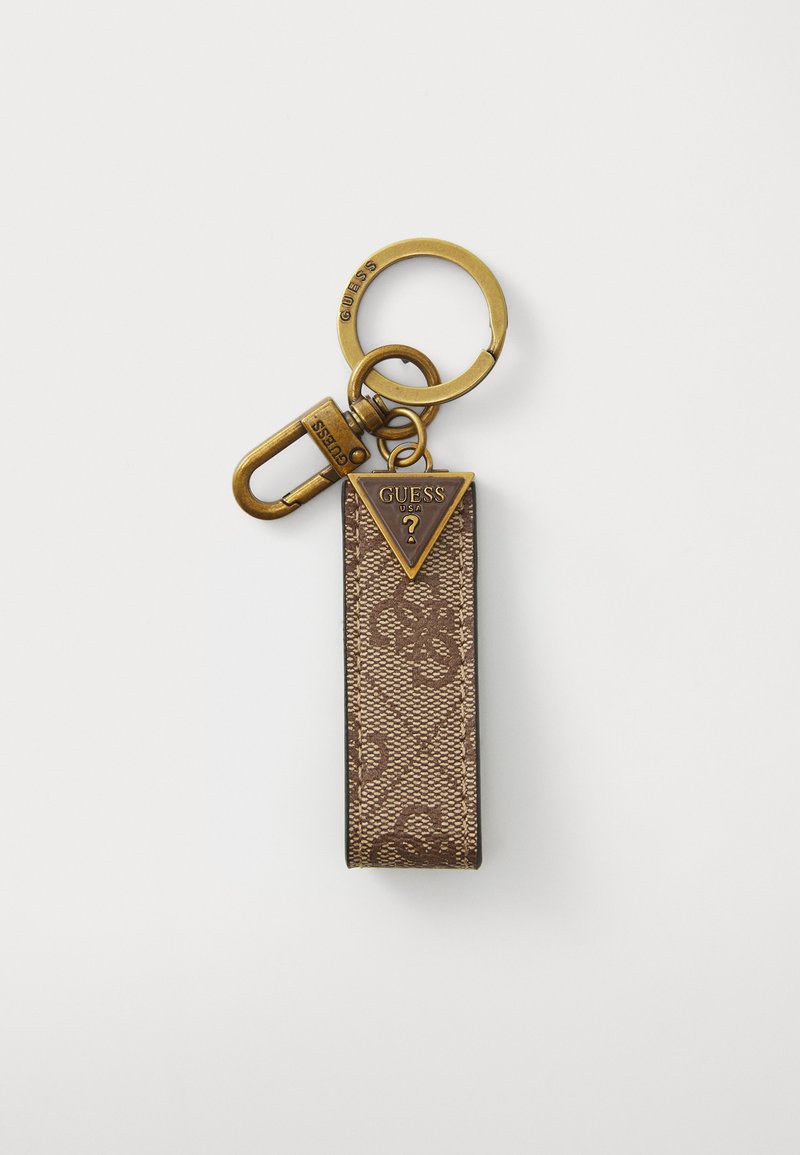 Porte-clés en tissu marron avec une étiquette métallique triangulaire portant l'inscription "GUESS USA" en relief, accompagnée d'un anneau et d'un clip dorés.
