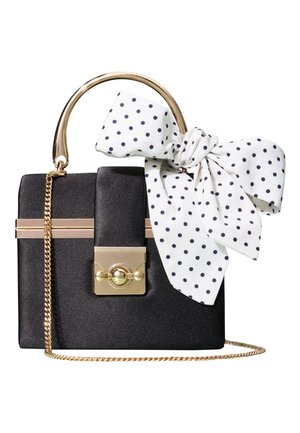 Sac à main rectangulaire noir avec poignée et chaîne dorées, avec un foulard blanc à pois noirs noué en nœud sur la poignée.