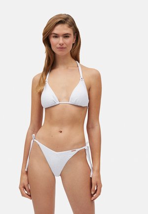 Conjunto de bikini blanco que presenta una parte superior triangular texturizada con tirantes halter y una parte inferior de corte bajo con lazos laterales ajustables.