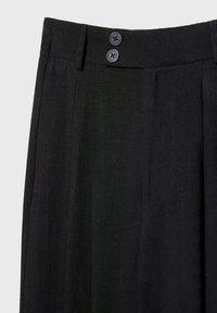 Pantalon noir taille haute avec deux boutons foncés à la ceinture et des passants pour ceinture, présentant une texture de tissu lisse.