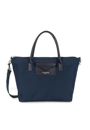 Sac en tissu bleu marine avec des poignées en cuir et une poche à rabat. Caractéristiques en métal argenté et une bandoulière amovible.
